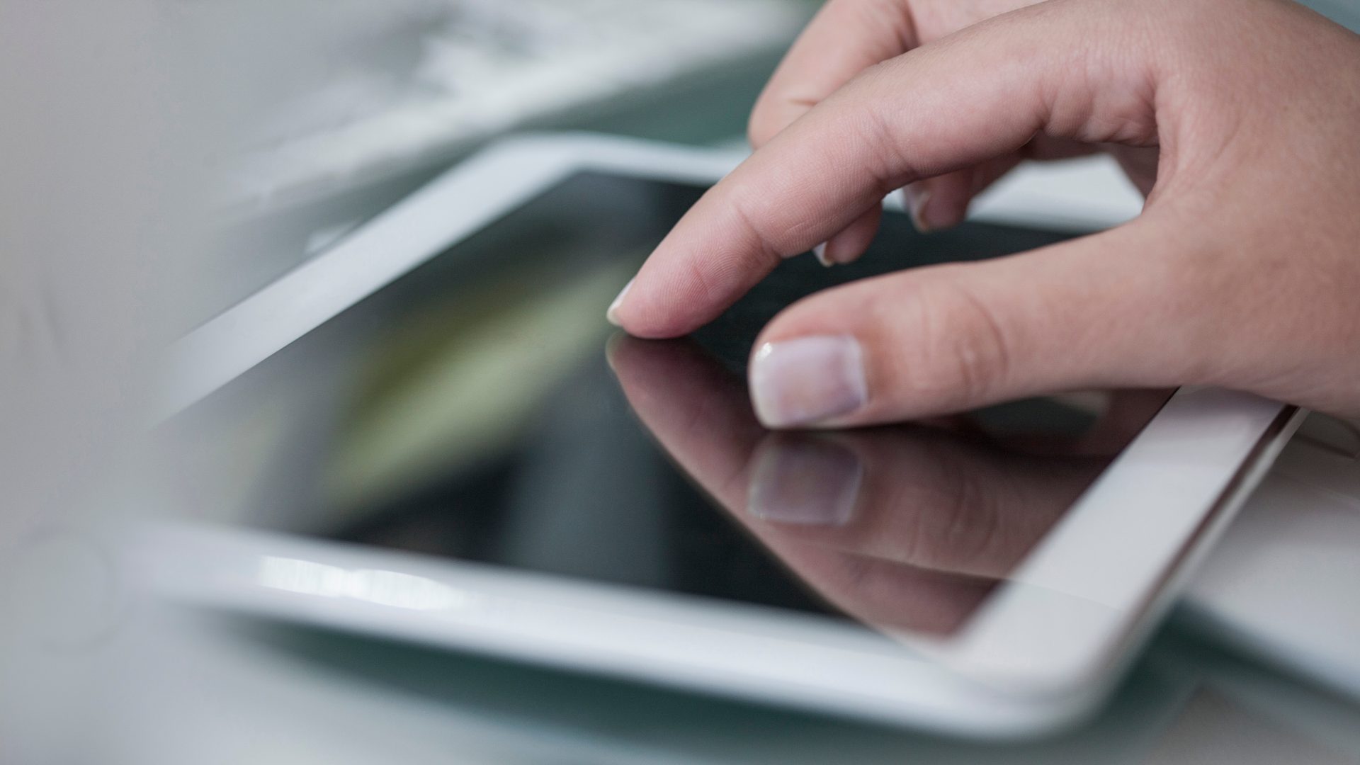 Das Bild zeigt eine Hand, die einen Tablet-Computer mit einem Touchscreen bedient.